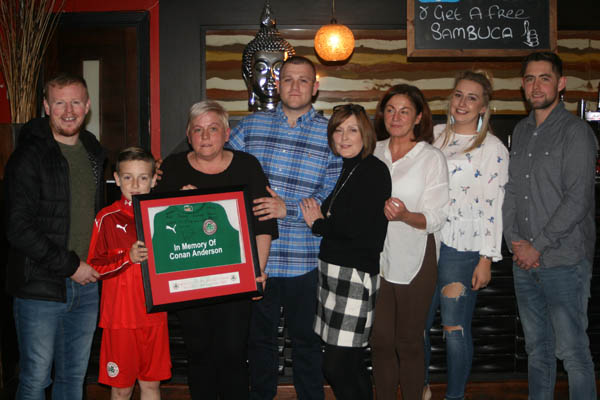 Former Reds star George McMullan and Nathan Farmer from Cliftonville U12s present the family of Conan Anderson with a signed framed jersey