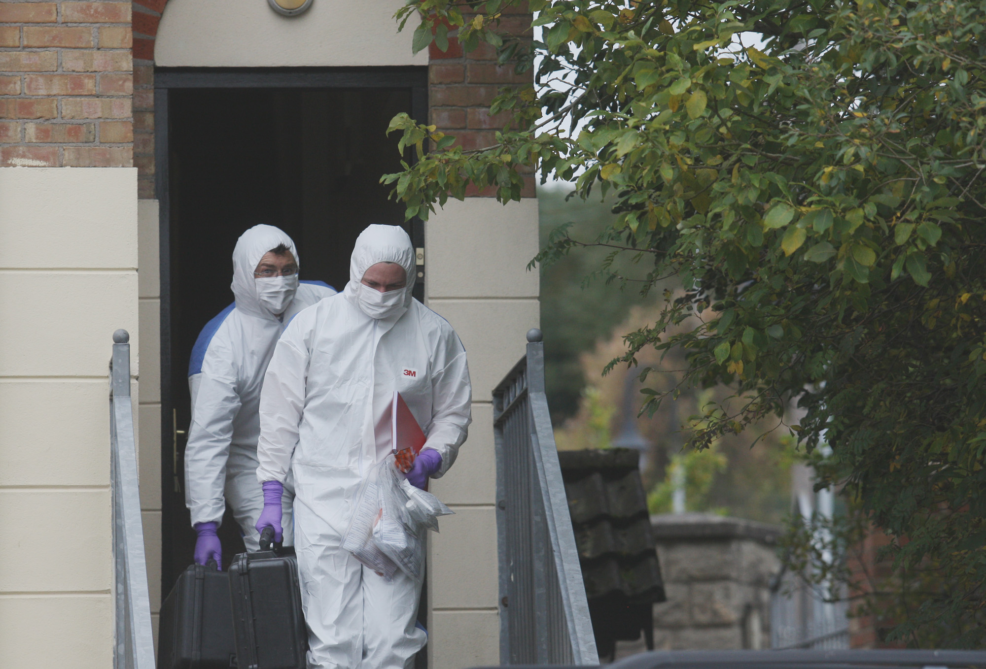 Police forensics officers leave the flat where the woman’s body was found