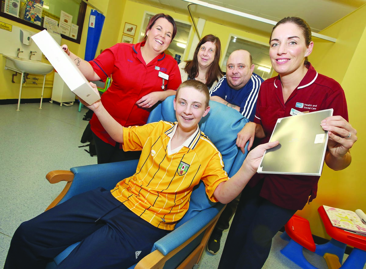 CHRISTMAS BOX: Robert Fields hands over the iPad to Alison Donnelly (Ward Manager) and Maureen McVeigh (Allergy Nurse Specialist) at the RVH, also pictured are mum Alexis and dad Bobby