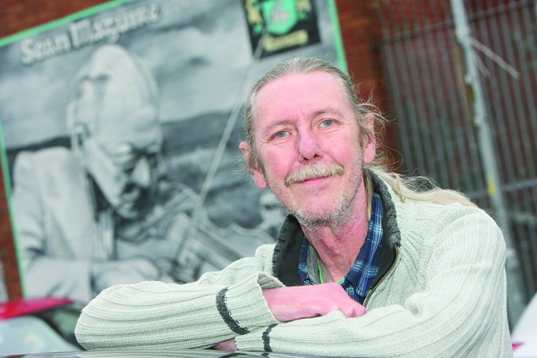 MUSIC MAN: Thomas ‘Maxi’ McElroy from the Andersonstown School of Music beside a mural of the famous Seán Maguire on the Falls 