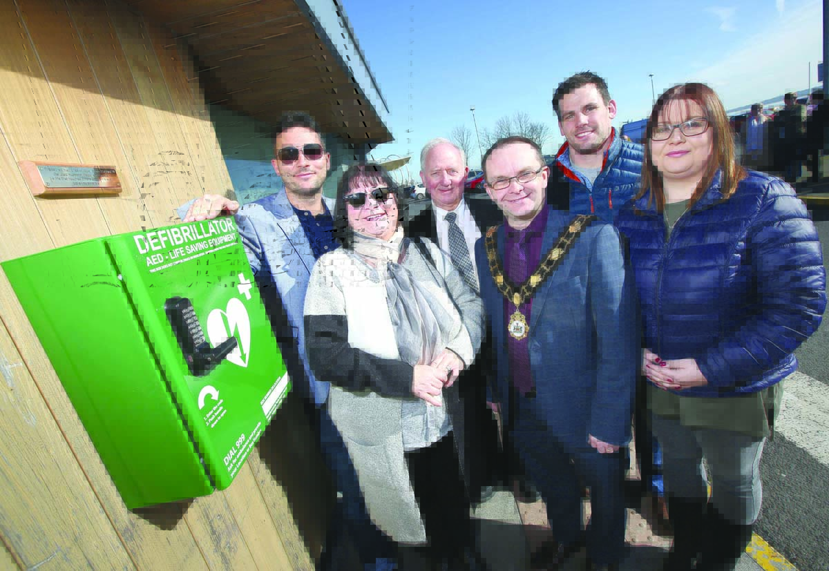 Mayor of Antrim and Newtownabbey, Councillor Paul Hamill, unveils the new defibrillator at Jordanstown Loughshore Park with Councillor Michael Maguire, Richard Lutton and Mark, Janice and Victoria Stone