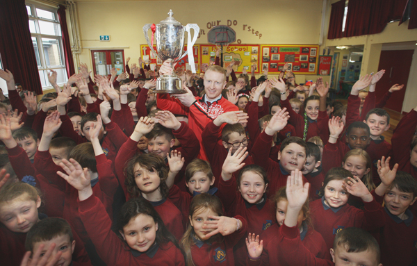 Lamh Dhearg senior footballer Brendan McComb with the Senior Championship cup at St Oliver Plunkett Primary School