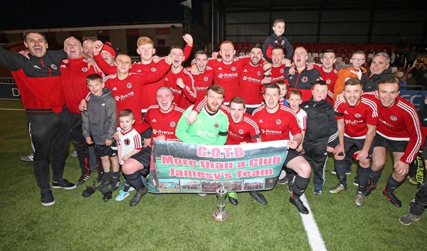 Willowbank’s players and management celebrate following their 2-1 win over Ballysillan Swifts in the final of the Cochrane Corry Cup final at Seaview last Wednesday night. The win secured a remarkable treble for the West Belfast club
