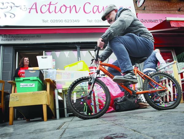 Daily Belfast photographer Thomas McMullan tries a bike out for size at the Action Cancer shop in Andersonstown as his colleague Jacqueline O\'Donnell looks doubtfully on