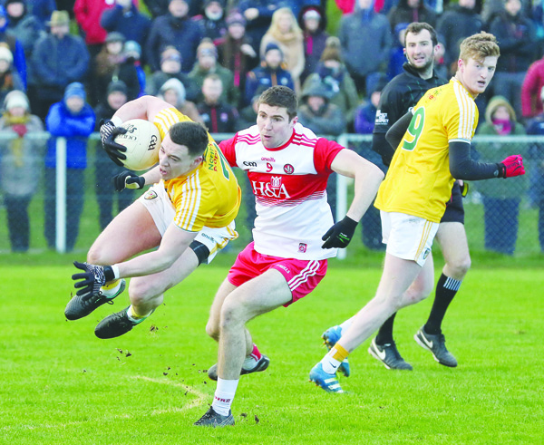 Antrim defender Declan Lynch secures possession ahead of Derry midfielder Ciaran McFaul during last Sunday’s Allianz League opener. The Saffrons suffered a narrow one-point loss at Corrigan Park and the skipper feels this Sunday’s clash against Wexford is now a “must-win” game for Antrim