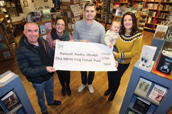Paid Ó Cianáin from Taca presents a cheque for £2,500 to Eibhlin Bhreathnach, Ryan Carlin, Odhran Nic Giolla Fhinnein and Mairead Nic Giolla Fhinnein from Naíscoil Aodha Dhuibh