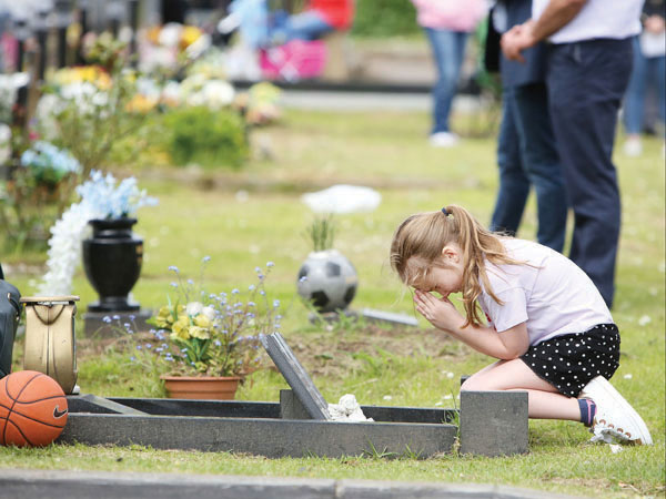 Erin Shannon prays at the family grave during Cemetery Sunday at Milltown