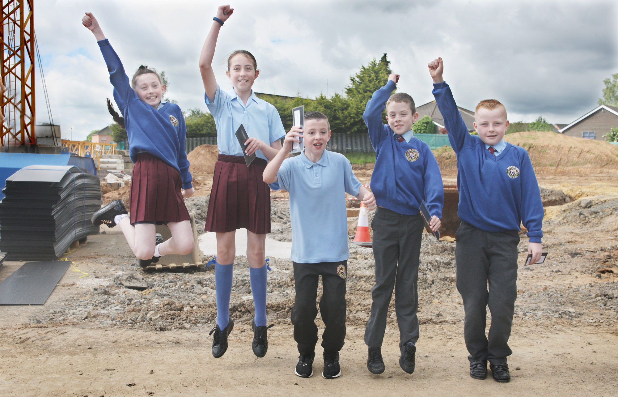 Holy Evangelists Primary School pupils Aoife, Holly Rose, Liam, Nathan and Aodhn jump with joy as Bishop Noel Treanor blesses the foundations of the new school building in Twinbrook