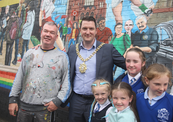 John Finucane unveiling a new mural celebrating West Belfast with artist Michael Doherty and local children on the lower Falls 