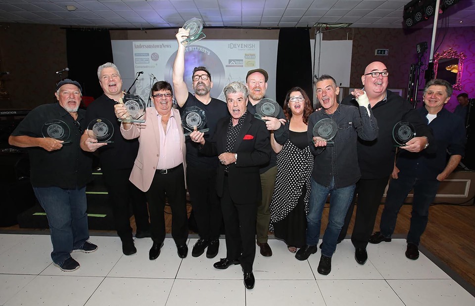 Rab McCullough, U105’s Johnny Hero, Des Lee, Brian Kennedy, Joby Fox, Jimmy Reilly, The Adventures’ Eileen and Pat Gribben, Terry Sharpe and James Peake celebrate their West Belfast Greatest Hits and Legends awards\n