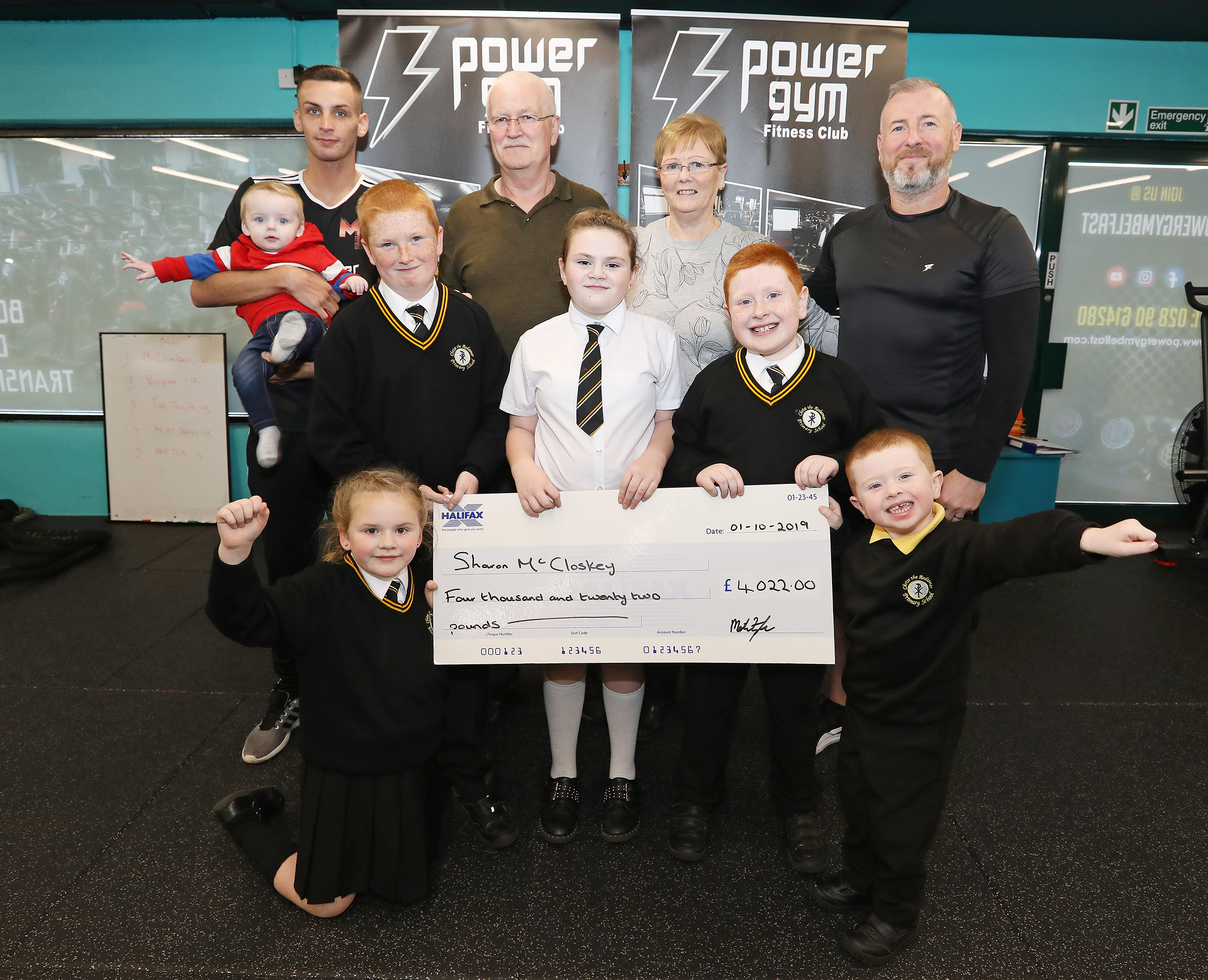 The parents of West Belfast’s ‘Sunflower’ Sharon McCloskey thank the community for all their fundraising efforts including staff and management from Twinbrook based Power Gym who held a white collar event in the Devenish Complex. Pictured are: Sharon McCloskey\'s parents John and Alice Whyte, Sharon\'s sons Joshua, Matthew and Caleb, also pictured are Charlotte and Grace Dunne and Power Gym’s Ciaran Cunningham and Mathew Fitzsimons 