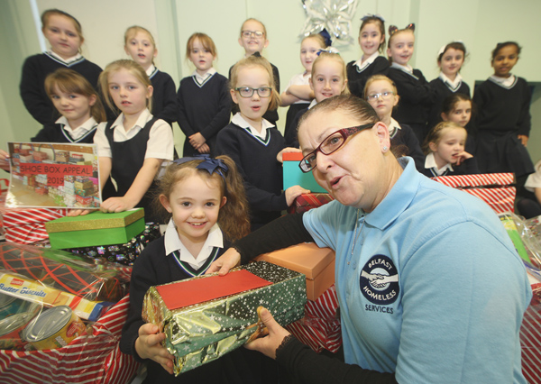 Jessica Mooney and her P4 class from Our Lady\'s Girls\' Primary School present Liz Rocks of Belfast Homeless Services with food and clothing, donated from their Shoebox Appeal