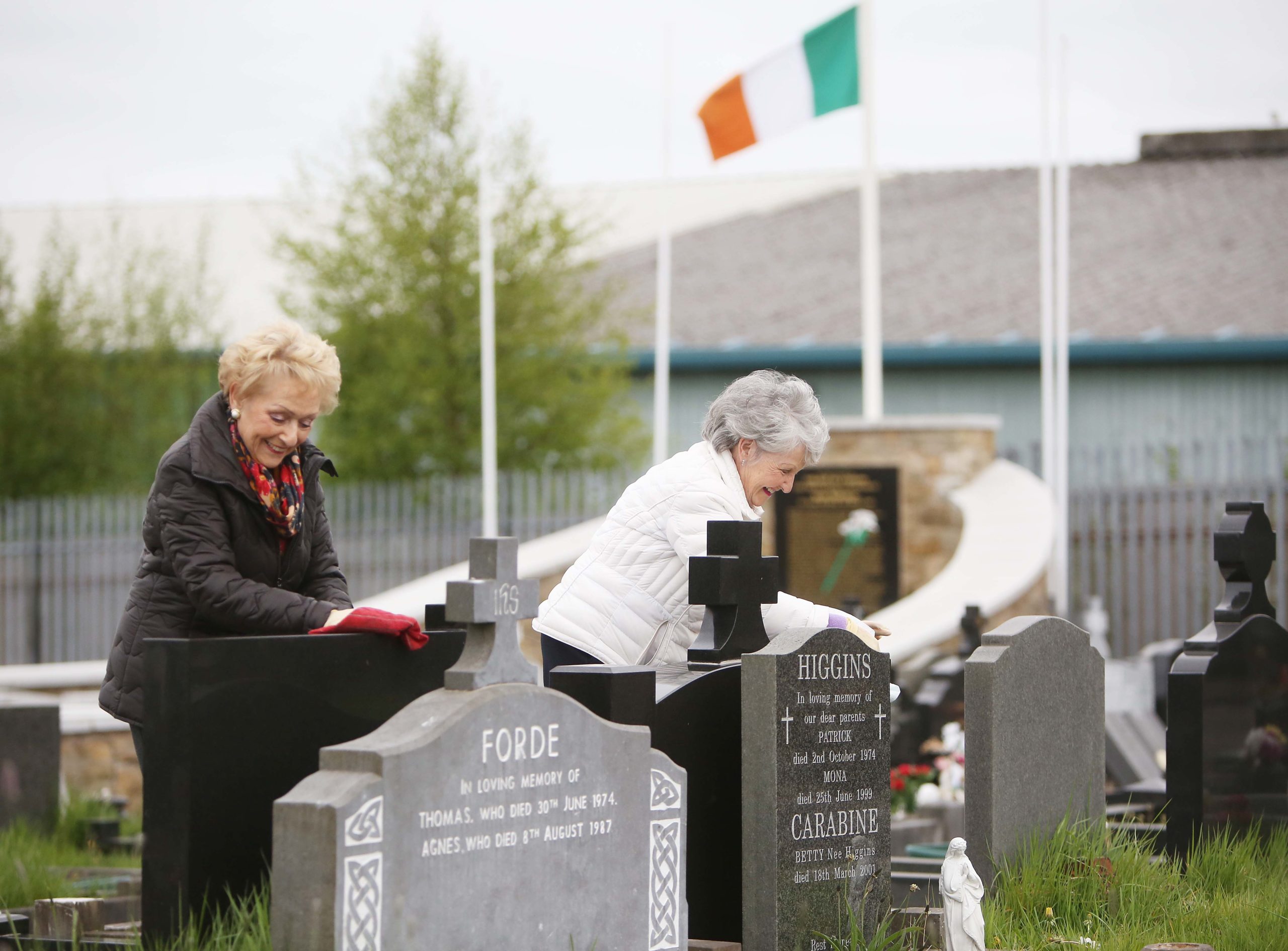 PAYING RESPECTS: Sisters Jo and Alice Quinn who are self-isolating together tidy relatives\' graves at Milltown Cemetery on Sunday.
