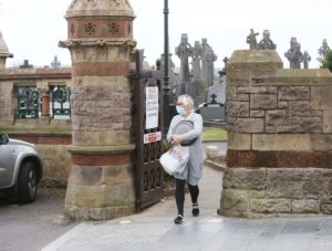 REOPENED: A woman leaves Milltown Cemetery on Sunday after tidying a grave