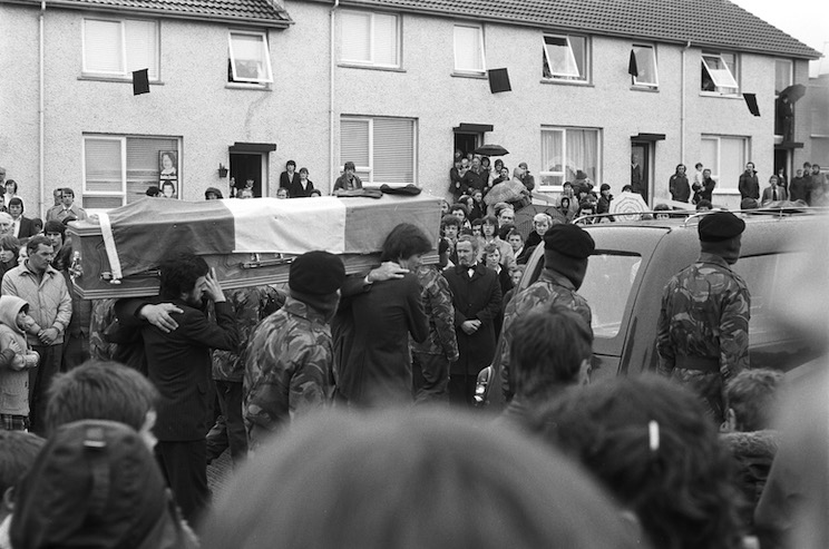 \"IRA MARTYR BOBBY SANDS DIES\": 7 May 1981, Owen Carron and Seán Sands carry the coffin of Bobby Sands through Twinbrook. Undertaker Tom Healey can also be seen. Photo by Basil McLaughlin.